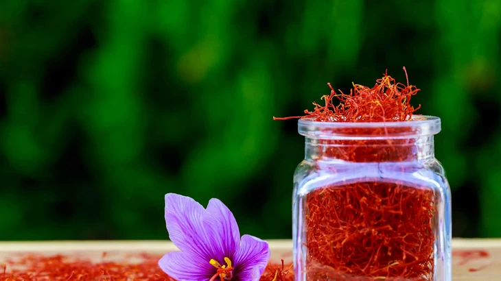 Saffron in glass jar next to Autumn Crocus flower